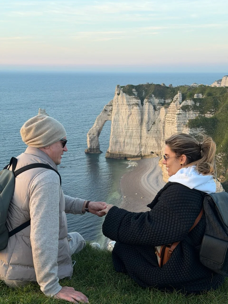 A couple sharing a quiet moment above the Étretat arch