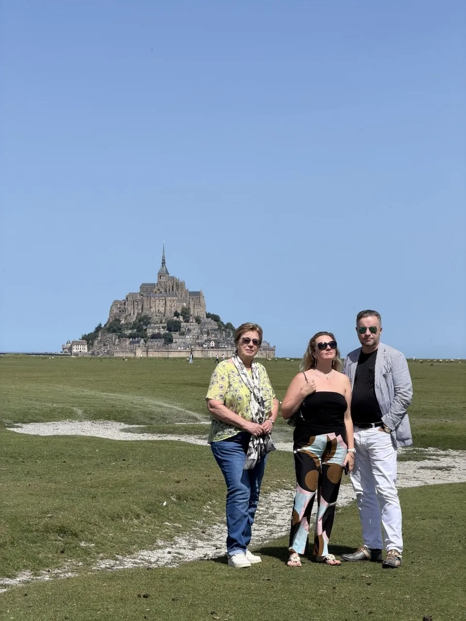 Three guests posing with Mont Saint-Michel in the distance