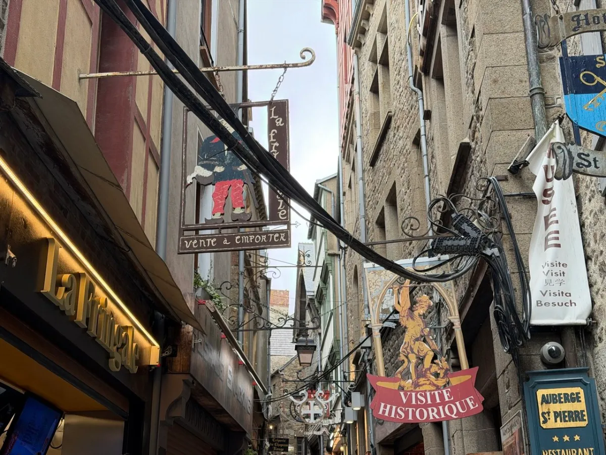 Historic shop signs lining a narrow street inside Mont Saint-Michel