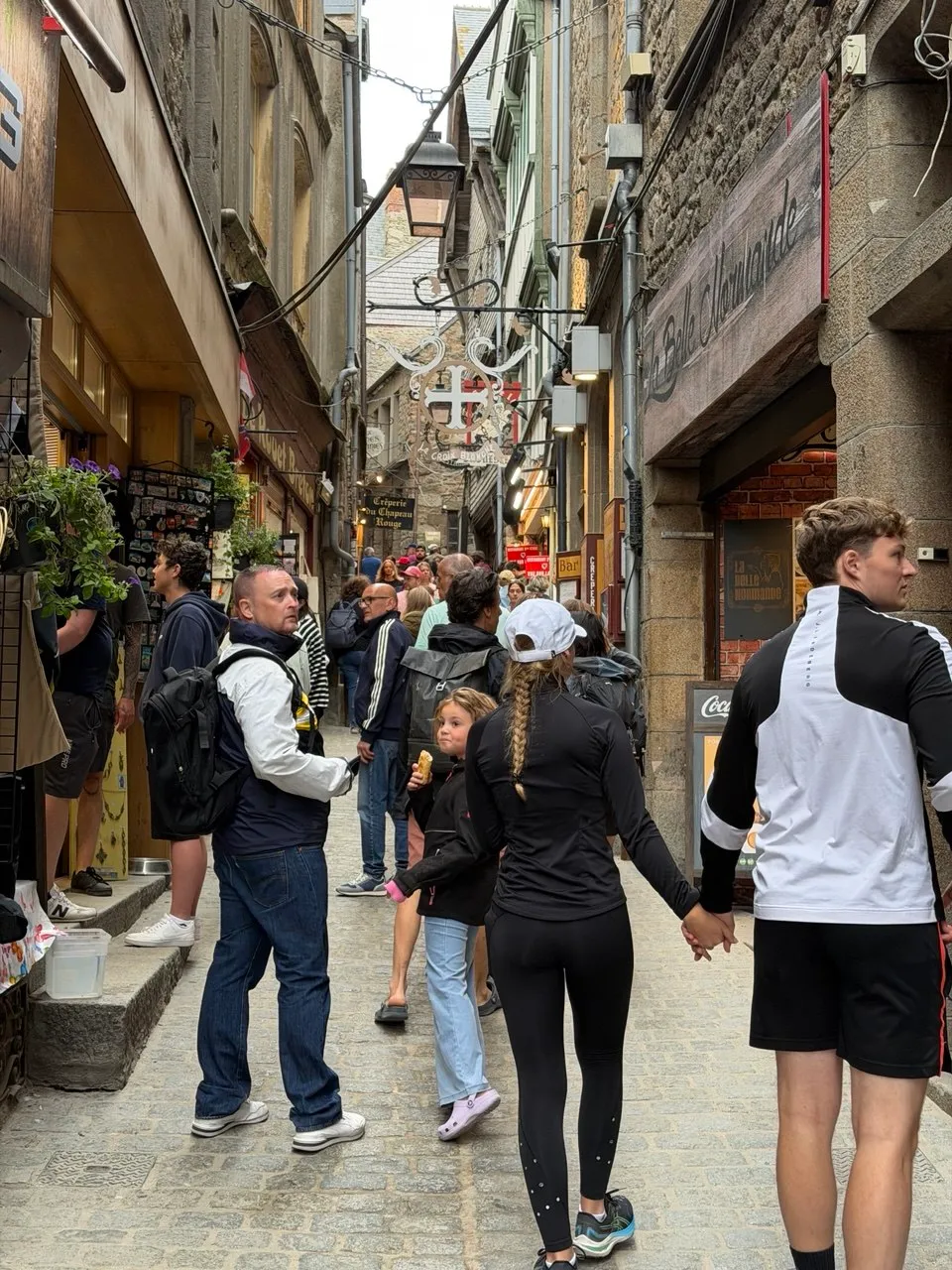 Visitors walking through a lively medieval street at Mont Saint-Michel